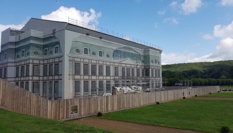 Slika na plahti je predstavitev gradu po Mansartovi prenovi. Monumentalno stopnišče pred vhodom so začasno odstranili zaradi težav nestabilnosti in ga bodo popolnoma sanirali.