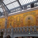 Restavrirane freske pavov tik pod stekleno streho v železnem ogrodju.